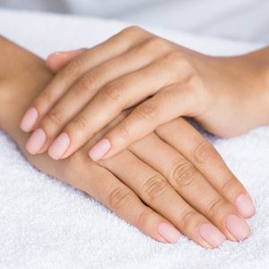 Nude manicure. Female hands on white towel, closeup